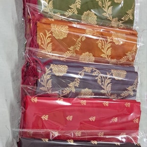 May include: A stack of seven fabric swatches in various colors, including blue, pink, green, orange, gray, red, and black. Each swatch features a gold floral pattern.