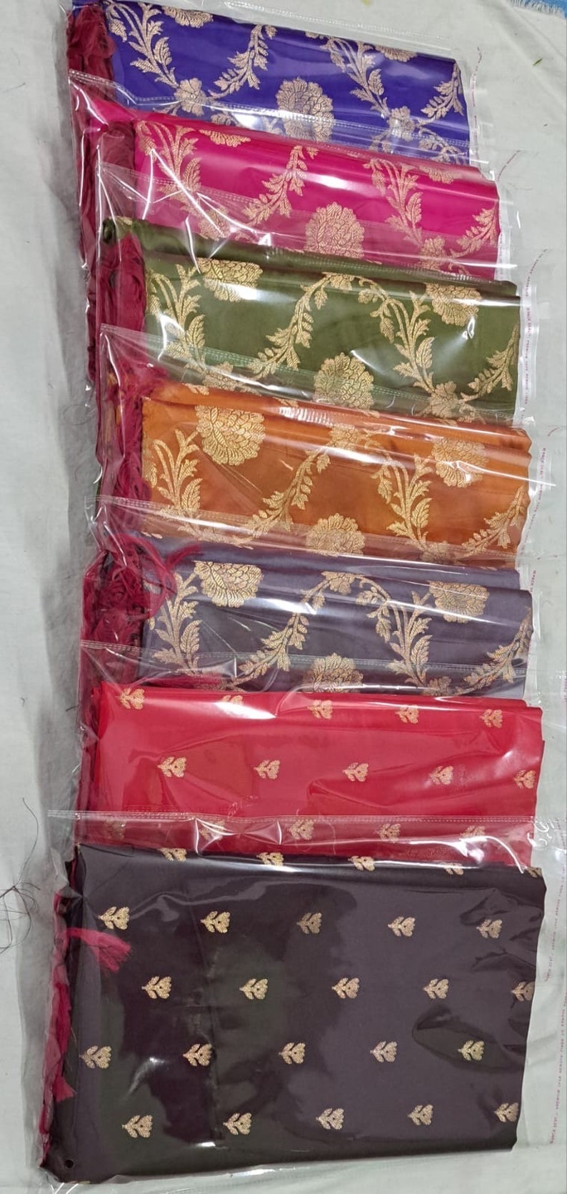 May include: A stack of seven fabric swatches in various colors, including blue, pink, green, orange, gray, red, and black. Each swatch features a gold floral pattern.