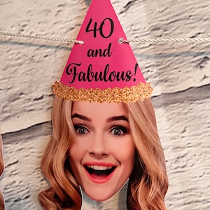 Pink and gold party banner with the text "40 and Fabulous!" on each end. The banner features a pink party hat with gold glitter and a woman's face with blonde hair.