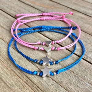 Puede incluir: Dos pulseras de la amistad con dijes de estrella plateados y dos pulseras de la amistad con dijes de corazón plateados. Las pulseras están hechas con hilo rosa y azul.