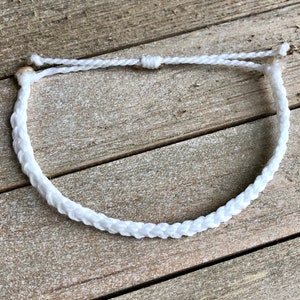 May include: White braided bracelet with a simple knot closure.