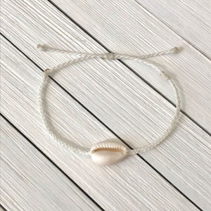 Peut inclure: Bracelet en cordon blanc avec un charme en coquillage blanc.