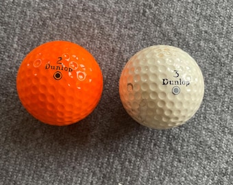 Vintage & cool pairing of golf balls bel. from the 1980's, a "Silver Max" Maxfli Dunlop and an orange "Blue Max" Maxfli Dunlop. Golf collect
