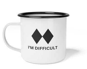 May include: White enamel mug with a black rim and handle. The mug features two black diamond shapes and the text "I'M DIFFICULT" in black. A humorous and bold statement for coffee or tea.