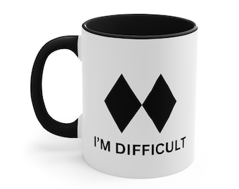 May include: White ceramic mug with a black interior, handle, and the text "I'M DIFFICULT." The mug features two black diamond shapes. A humorous and bold design for coffee or tea.