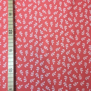 May include: Coral fabric with a white leaf pattern. The fabric is measured in inches.