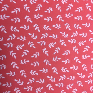 May include: A red fabric with a white leaf pattern. The leaves are small and simple, and they are repeated all over the fabric.