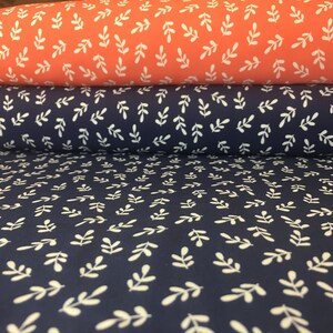 May include: Two rolls of fabric with a white leaf pattern. The top roll is coral pink and the bottom roll is navy blue.
