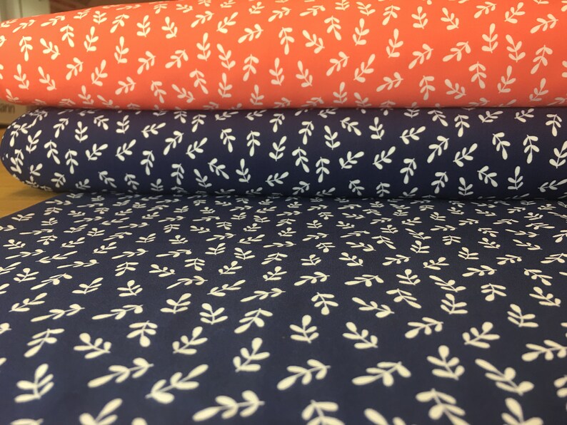 May include: Two rolls of fabric with a white leaf pattern. The top roll is coral pink and the bottom roll is navy blue.