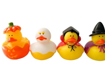 May include: Four Halloween-themed rubber ducks. One is a pumpkin, another is white, and the other two are dressed as a vampire and a witch. The ducks are yellow with orange beaks and are set against a white background.