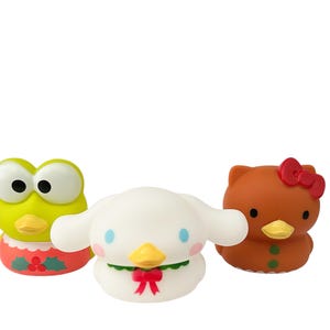 May include: Three cartoon character figures: a green frog, a white dog-like creature, and a brown cat-like figure. The frog has large eyes and a red and green trim. The dog has blue accents and a red bow. The cat has a red bow.