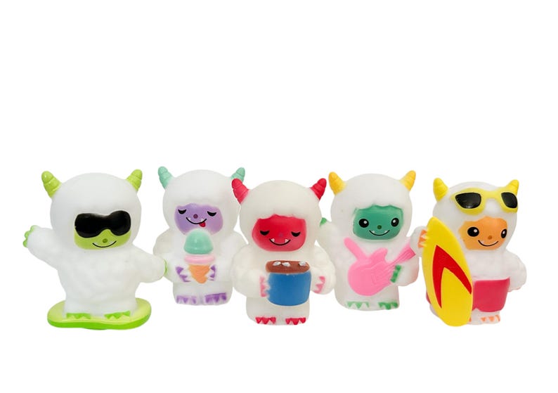 Puede incluir: Cinco figuras de monstruos blancos y esponjosos con caras y accesorios coloridos. Uno lleva gafas de sol y una base verde, otro sostiene un cono de helado y un tercero una taza. El cuarto toca una guitarra rosa, y el &uacute;ltimo tiene gafas de sol y una tabla de surf.