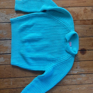 Könnte beinhalten: Ein hellblauer Strickpullover mit Rippenstruktur.