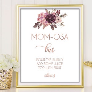 May include: Printable sign for a "Mom-osa Bar" with a watercolor floral design in shades of pink and purple. The sign reads "Pour the bubbly, add some juice, top with fruit, cheers".