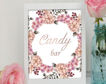 May include: A white frame with a floral design and the text "Candy bar" in gold lettering. The frame is sitting on a white surface with a pink rose in the foreground.