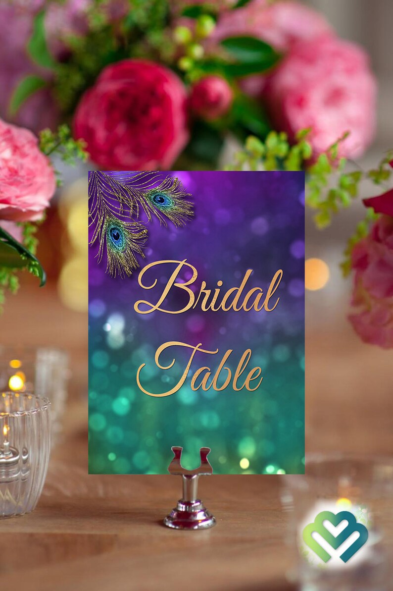 May include: A purple and teal table number card with gold glitter and peacock feathers. The card says "Bridal Table" in gold script.