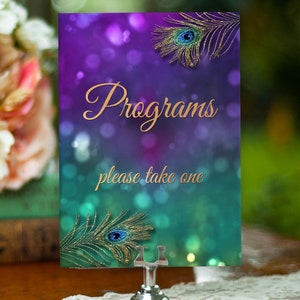 Könnte beinhalten: Ein lila-türkisfarbenes Hochzeitsprogramm-Schild mit goldenem Glitzer und Pfauenfedern. Das Schild lautet "Programme bitte nehmen Sie eins".