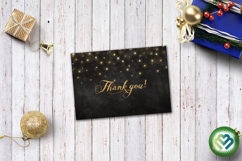 May include: A black card with gold glitter and the text "Thank you!" on a white wood background.