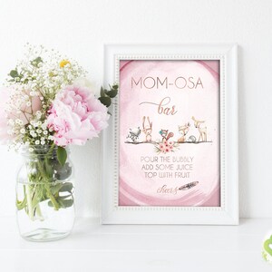 May include: A pink and white printable sign with the text "Mom-osa Bar" and a graphic of woodland animals. The text below the animals reads "Pour the bubbly, add some juice, top with fruit, cheers!"