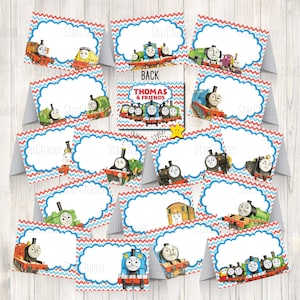 May include: A collection of folded Thomas & Friends themed place cards featuring various train characters, a red and blue chevron border, and a central cloud-shaped white space for writing names, with one card labelled BACK and THOMAS & FRIENDS.