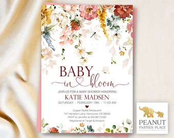 Op de afbeelding: Een bloemige babyshower-uitnodiging met een roze en witte achtergrond. De tekst luidt "Baby in bloom" en bevat de naam "Katie Madsen" en de datum "19 februari".