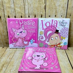 May include: Three pink children's books with colourful illustrations. The first book is titled "Posie the Kitten in Pink". The second book is titled "Lola the Lollipop Fairy". The third book is titled "Pennie the Pinkest Polar Bear".