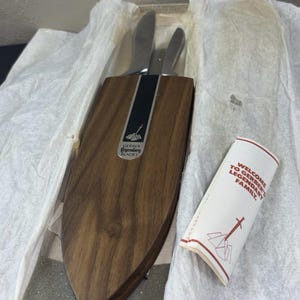 May include: A set of Gerber Legendary Blades knives in a wooden holder, presented in a box with tissue paper. The holder has a dark wood grain finish with a black stripe and the Gerber logo. A small paper insert reads "Welcome to Gerber's Legendary Family."