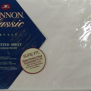May include: A packaged twin fitted sheet by Cannon Classic Percale. The packaging features a navy blue and white label with the brand name and product details. The sheet is guaranteed to fit and is designed for deep pocket mattresses up to 13 inches.