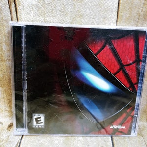 May include: A video game case with a black background and a red and blue image of Spider-Man's mask. The case has an "Everyone" rating from the ESRB and the Activision logo.