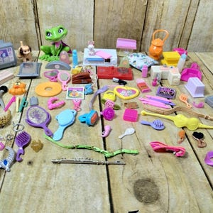 May include: A collection of colorful plastic toys for a dollhouse, including furniture, accessories, and a frog figurine.