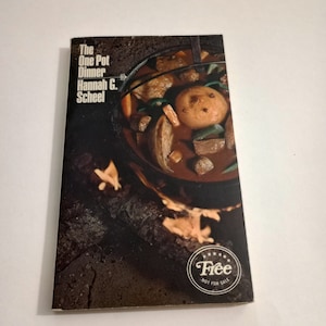 May include: A cookbook titled "The One Pot Dinner" by Hannah G. Scheel. The cover features a close-up of a pot of stew cooking over a fire. The book is labeled "Free, Not For Sale."