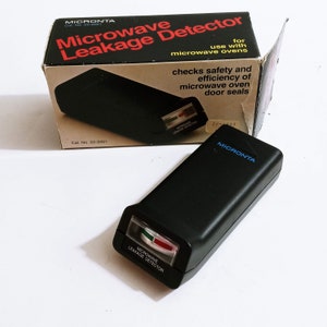May include: A black Micronta Microwave Leakage Detector with a red and green indicator, and the text "Microwave Leakage Detector". The box reads "checks safety and efficiency of microwave oven door seals."