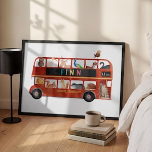 Puede incluir: Impresión enmarcada de un autobús de dos pisos rojo de Londres, con ilustraciones de animales como pasajeros. El nombre "FINN" se muestra en el autobús, junto con la fecha "15 DEC". La obra de arte está enmarcada en negro sobre un fondo blanco.