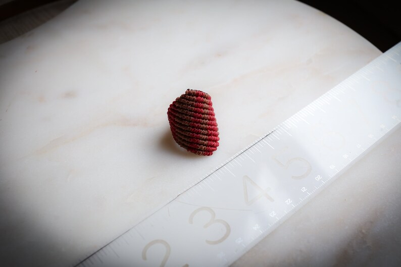 K&ouml;nnte beinhalten: Ein geh&auml;kelter Ring mit einem Spiraldesign in Rot und Braun.