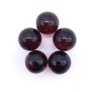 May include: Five dark purple glass marbles with a speckled appearance.