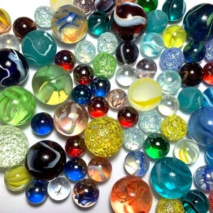 May include: A collection of colorful glass marbles in various patterns and colors, including clear, blue, green, red, and white. The marbles are arranged in a random pattern on a white surface.