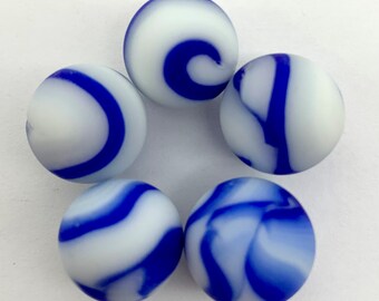 Könnte beinhalten: Fünf weiße Murmeln mit blauen Wirbelmustern. Die Murmeln sind sternförmig angeordnet, jede mit einem einzigartigen Design aus blauen Streifen und Wirbeln. Die Murmeln sind ein klassisches Spielzeug.