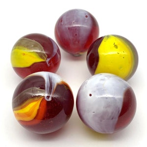 May include: Five glass marbles with red, white, and yellow swirling patterns. The marbles are round and smooth.