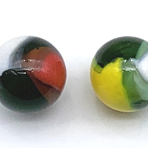 May include: Two glass marbles with colorful swirls. One marble is green, white, and yellow. The other marble is black, white, red, and green.