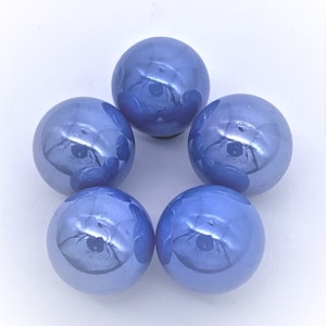 May include: Five blue glass marbles with a pearlescent finish. The marbles are arranged in a circle on a white surface.