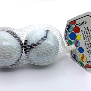 May include: Two white marbles with black swirl designs in a clear plastic bag with a white label that reads "Panda" and "2 Marbles-Billes" with the company name "Montrose" printed on the label.