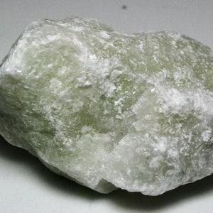 May include: A large, rough, light green and white rock with a crystalline texture.