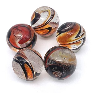 May include: Five glass marbles with swirling patterns of black, orange, and white. The marbles are arranged in a circle.