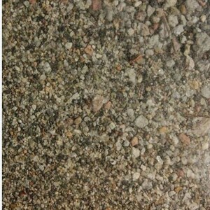 May include: A close-up of a variety of small, gray, brown, and white stones. The stones are tightly packed together, creating a textured surface.
