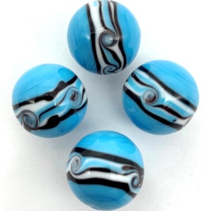 May include: Four blue glass marbles with white and black swirling patterns. The marbles are round and smooth.