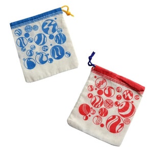 May include: Two small, off-white drawstring bags. One has a blue rim and blue circular designs, the other has a red rim and red circular designs. The designs include various patterns and the text "HOUSE OF MARBLES".