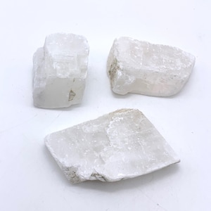 May include: Three white selenite crystal clusters, each with a unique shape and texture. The crystals are opaque and have a slightly milky appearance.