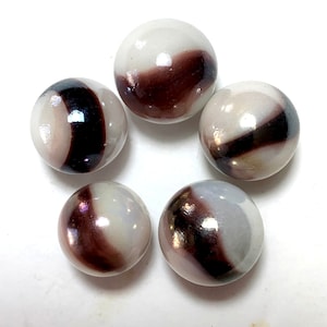 May include: Five white and brown swirl glass marbles. The marbles have a shiny, iridescent finish.