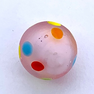 May include: A pink glass marble with yellow, orange, red, and blue polka dots.