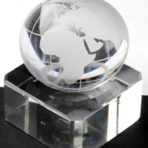 May include: A clear glass globe with a white etched map of the world sits on a clear glass square base.